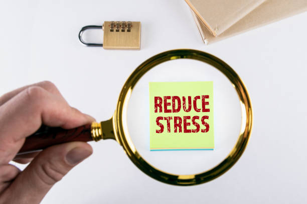 istock REDUCE STRESS. Magnifying glass in hand. Padlock and books on a white table 1291238712