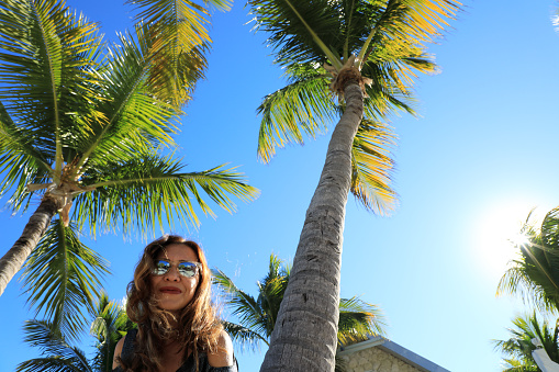portrait of mid adult woman with palm trees over sunny blue sky in Key West, Florida
