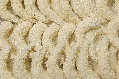 Lots of breaded shrimp ready to cook. A semi-finished dish. Shrimp background in food casing.