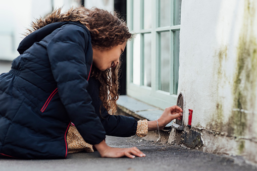 Close-up of a mixed race girl looking at a fairy door outdoors in Polperro, Cornwall.