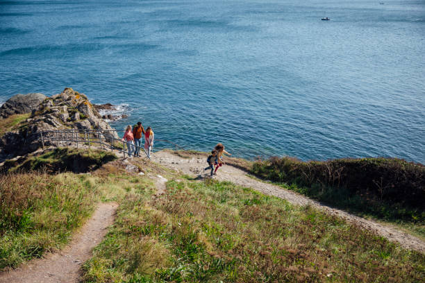 Follow the Leaders A family walking up a rock footpath along the cliff edge of Polperro, Cornwall. The two youngest children are running ahead of the parents and eldest daughter. cornwall england photos stock pictures, royalty-free photos & images