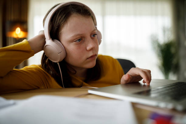 istock Bored school girl having using laptop for studying at home 1291246560