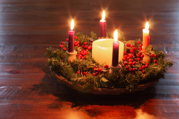 istock Advent wreath on dark wood table, candles lit 1291247581
