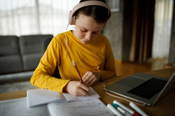istock Smiling cute little girl having online school class 1291247591