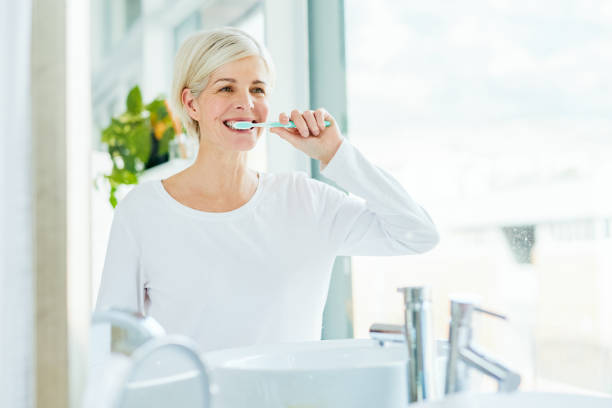 healthy teeth make us look and feel good - brushing teeth women toothbrush brushing imagens e fotografias de stock