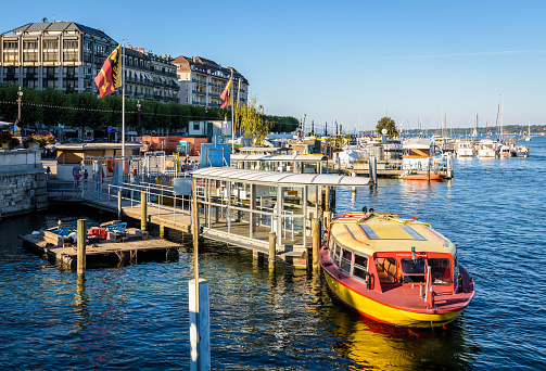 Geneva, Switzerland - September 8, 2020: A Mouettes Genevoises water bus is moored at the landing stage of the M1 line in the Paquis pier at the end of the afternoon.