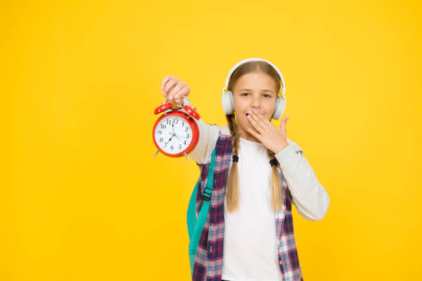 Classes schedule. Schoolgirl hold alarm clock yellow background. School timing concept. Beginning of lessons. Time go school. School time. Happy girl hold alarm clock counting minutes. Knowledge day.