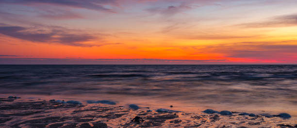 paesaggio marino panoramico al tramonto con raggi del sole rossi su onde morbide sulla bassa spiaggia di marea - cape cod bay foto e immagini stock