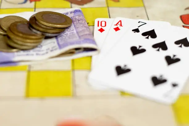 Photo of Table with cards and indian currency note and coins placed showing gambling going on in family and friend gatherings during diwali, new year and other fun gatherings