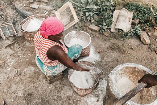 overhead view on african midaged woman sieving cassava flour in Malawi village