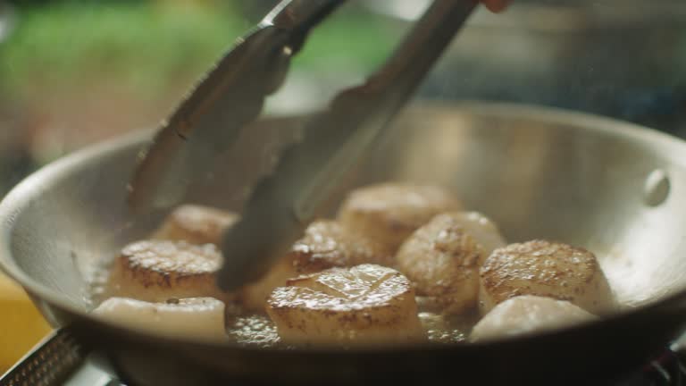 SLO MO CU Chef flips half-cooked scallops over in a skillet