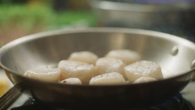 SLO MO CU Chef adds cooking oil to a skillet full of fresh scallops