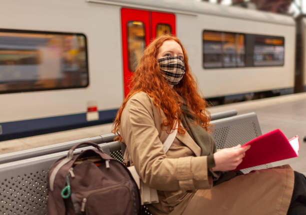 istock Student girl wearing a face mask checks the clock while sitting on a bench and studying 1291267525
