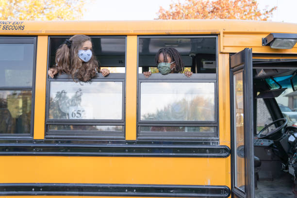istock Happy children looking out school bus window 1291268311
