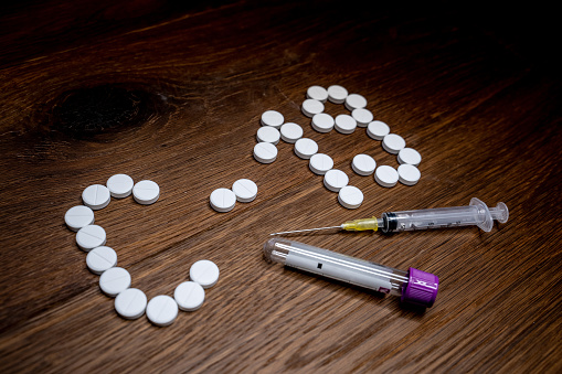 Nasal Swab in Test Tube With Syringe and Pills on Table.