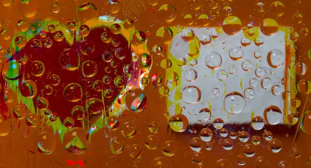 Multi colored drops of water are located on a yellow-red background with a red-green silhouette of a heart and a place for an inscription. Abstract fantasy. 3D render.