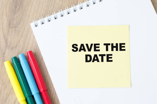 istock Text Save the date text on yellow paper with notepad on office desk, business concept 1291270097