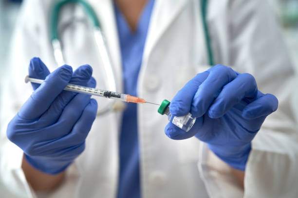 istock Close up of cropped hands inserting syringe into vial 1291270973