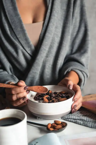 Photo of Closeup of bowl with fresh oatmeal and spoon in woman hands, healthy and nutritive breakfast concept.