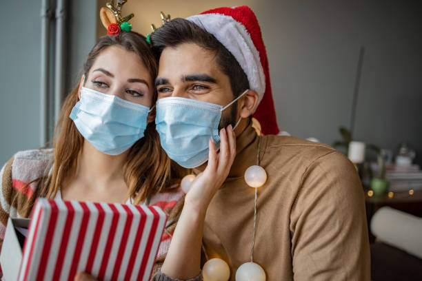 istock Couple at home with protective face mask celebrating Christmas 1291272134