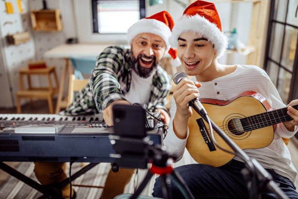 Father and son singing and playing music Father and son have a video call with friends during the Christmas holidays, during the pandemic COVID-19 father and son guitar stock pictures, royalty-free photos & images