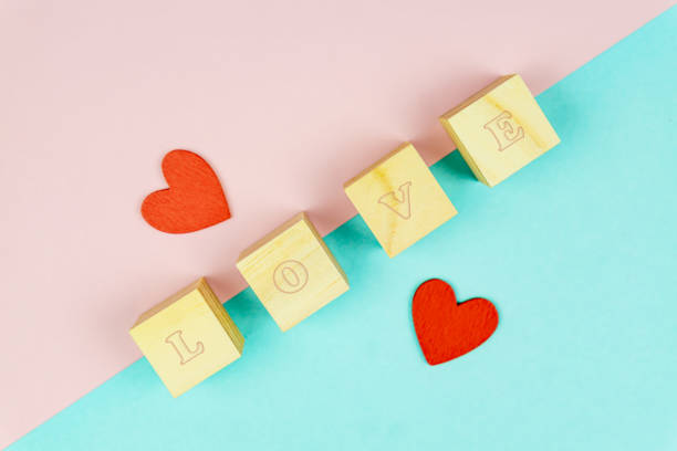 istock Red hearts and wooden cubes on pink and blue background. Creative flat lay with copy space. Festive greeting card for St Valentines day. Mockup 1291272821
