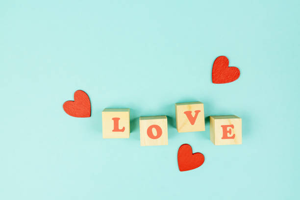 istock Red hearts and wooden cubes with text LOVE on blue background. Creative flat lay with copy space. Festive greeting card for St Valentines day. 1291272830