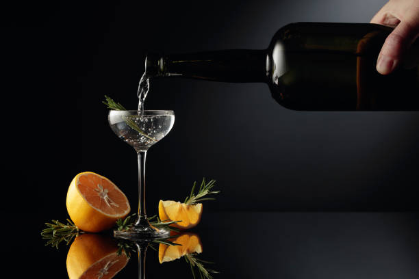 Gin with lemon and rosemary on a black reflective background.