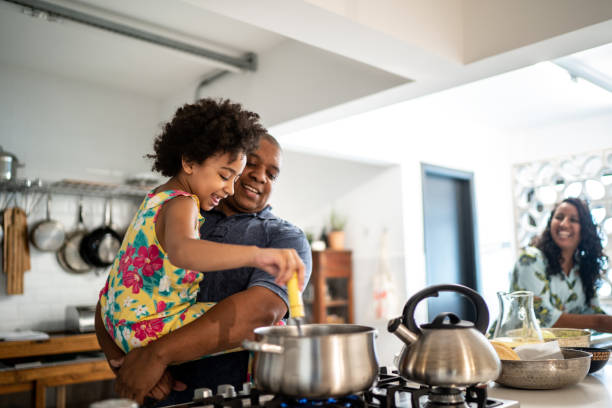 Girl in father's arms helping him cooking at home Girl in father's arms helping him cooking real kitchen stock pictures, royalty-free photos & images