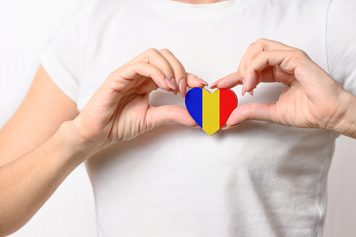 Love Romania. The girl holds a heart in the form of the flag of Romania on her chest. Romanian patriotism concept