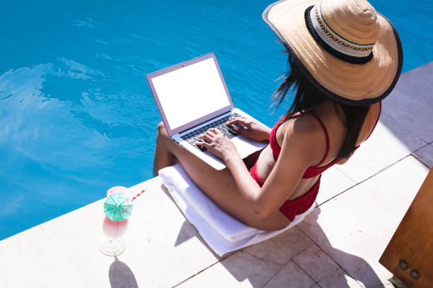 istock Mixed race woman at home using laptop by the pool 1291273348