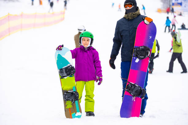 istock Instructors teach a child on a snow slope to snowboard 1291274085