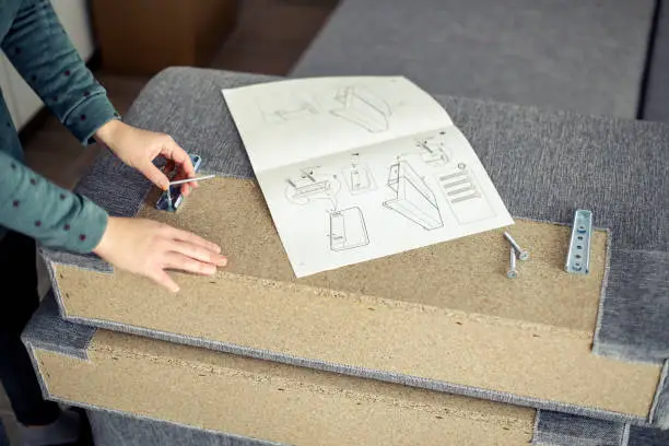 Young woman assembling a sofa. Unrecognizable Caucasian female.