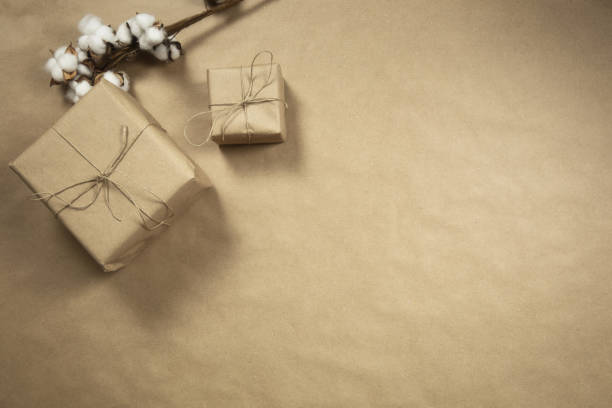 istock Two gift boxes wrapped in plain brown recycled paper with rope on brown background texture top view, present and recycle concept, copy space, space for text 1291276540