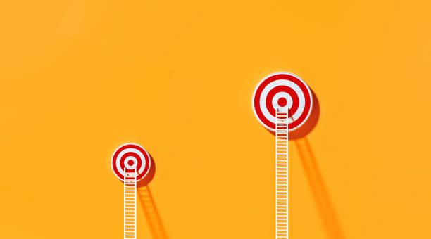 istock White Ladders Leaning on Two Red Bull's Eye Targets  on Yellow Wall 1291278167