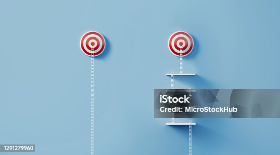 istock White Ladders Leaning on Two Red Bull's Eye Targets on Blue Wall 1291279960