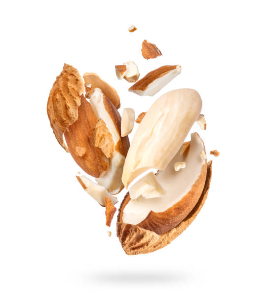 istock Crushed dried almonds with shell in air close up, isolated on white background 1291283533