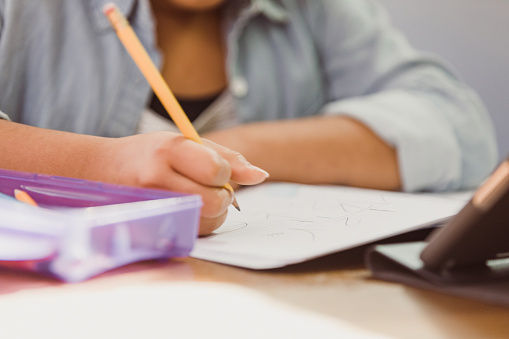 Unrecognizable girl fills in worksheet for school worksheet with pictures