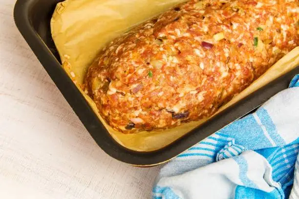 Freshly prepared meatloaf ready for the oven with ingredients. Minced meat with chili spices and sausage. Making classic meatloaf with ground beef.