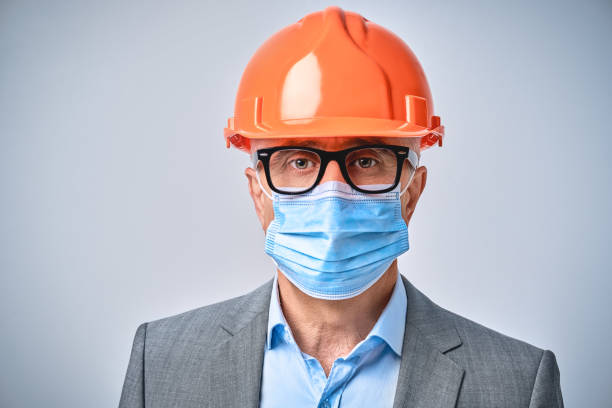 istock Businessman in orange helmet posing in studio 1291287987