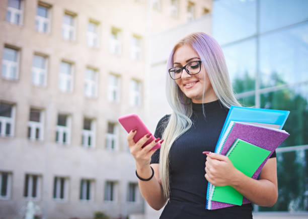 istock Young student girl using smart mobile phone to check social media platforms - Millennial influencer posting new content while walking on a university campus 1291290031