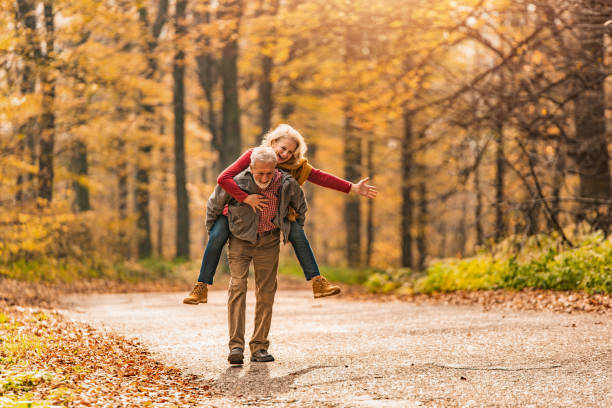 森の道で一緒に楽しんで遊び心のあるエネルギッシュなシニアカップル。 - senior adult fun autumn senior couple ストックフォトと画像
