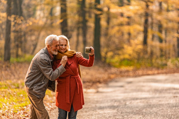 istock Happy senior couple standing on a forest road and taking a selfie. 1291290802