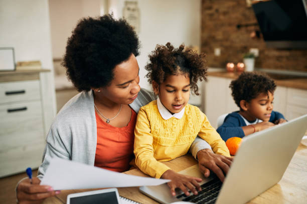 istock Black working mother and her daughter using laptop at home. 1291294455