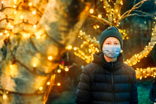 istock Young boy enjoying Christmas lights outdoors wearing face mask 1291295190