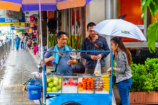 Buying food and fruits at a street food stand in Bangkok Thailand.