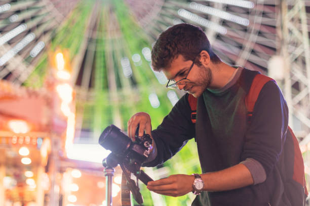 istock Young man taking photos at carnival fair at night 1291298421