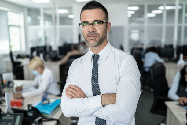 istock Confident business manager standing middle of office 1291299873