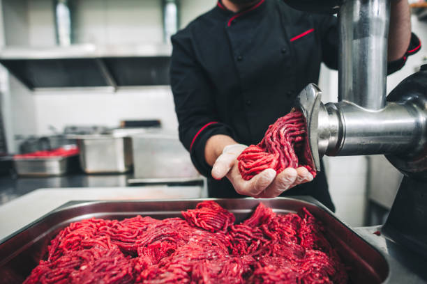 male chef butcher doing fresh ground beef on the meat grinder - meat grinder ground beef meat imagens e fotografias de stock