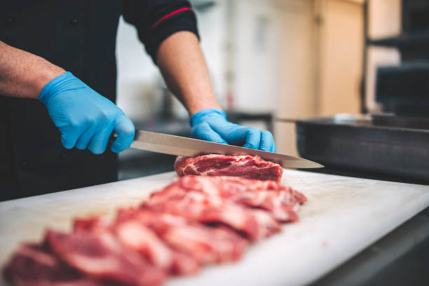 istock Male butcher cut raw meat with sharp knife in restaurants kitchen 1291299950